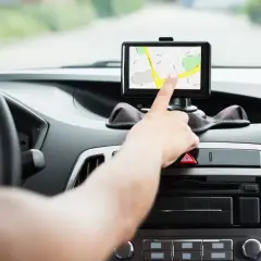 Ręka dotyka ekranu nawigacji, pomagając wybrać najlepszy gps do samochodu.