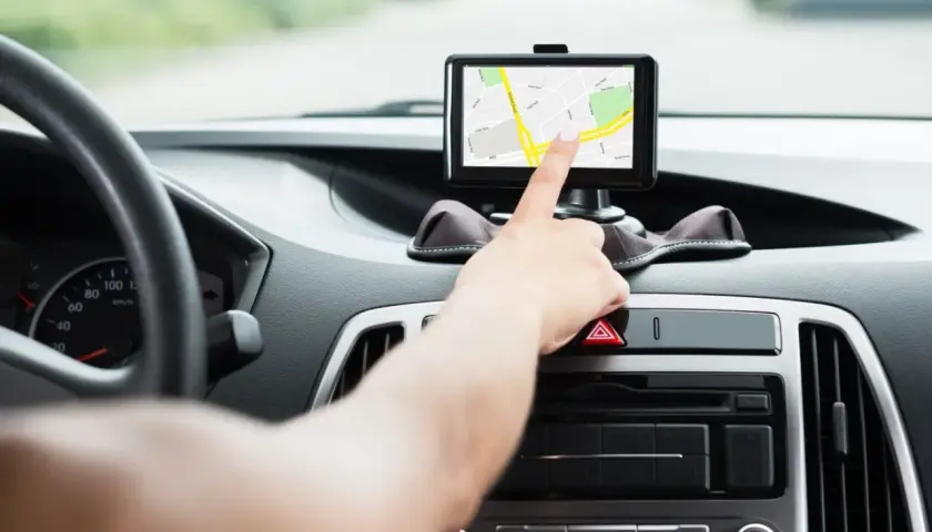 Ręka dotyka ekranu nawigacji, pomagając wybrać najlepszy gps do samochodu.